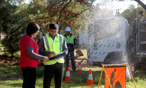 Crew fixing water main break with customer and Customer Liaison Officer